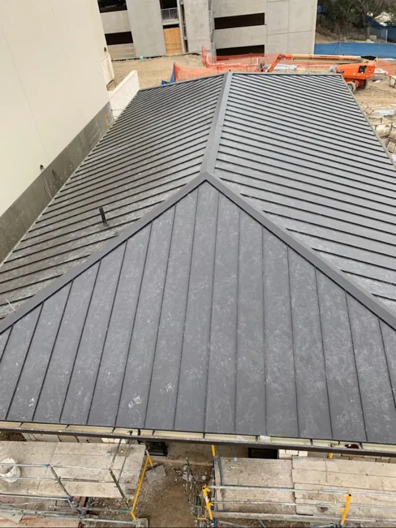 Commercial metal roof construction with crane equipment in Marquette